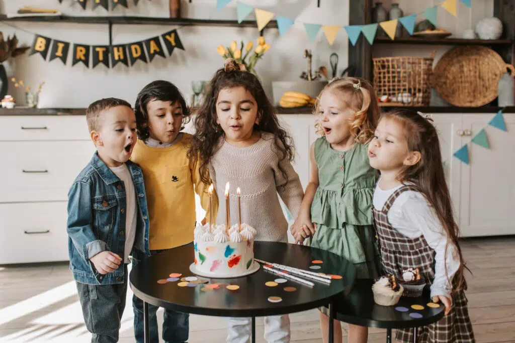 kids blowing out candles on birthday cake