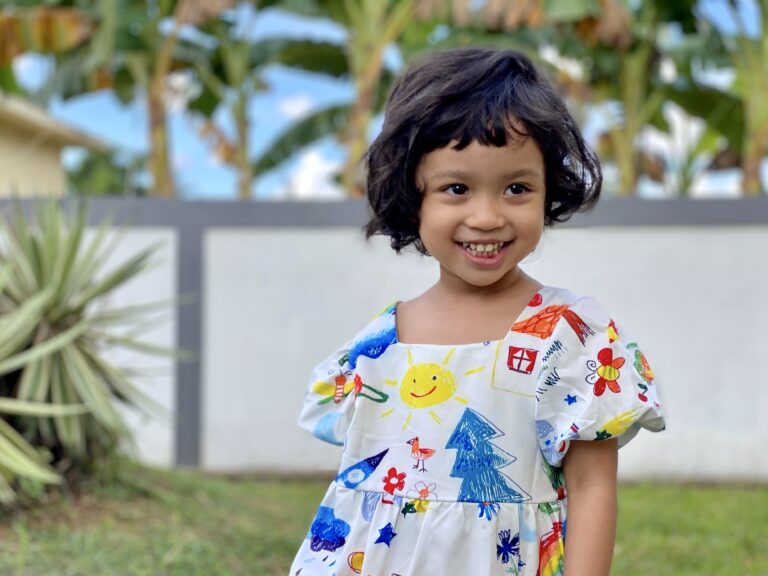 girl in backyard in dress smiling