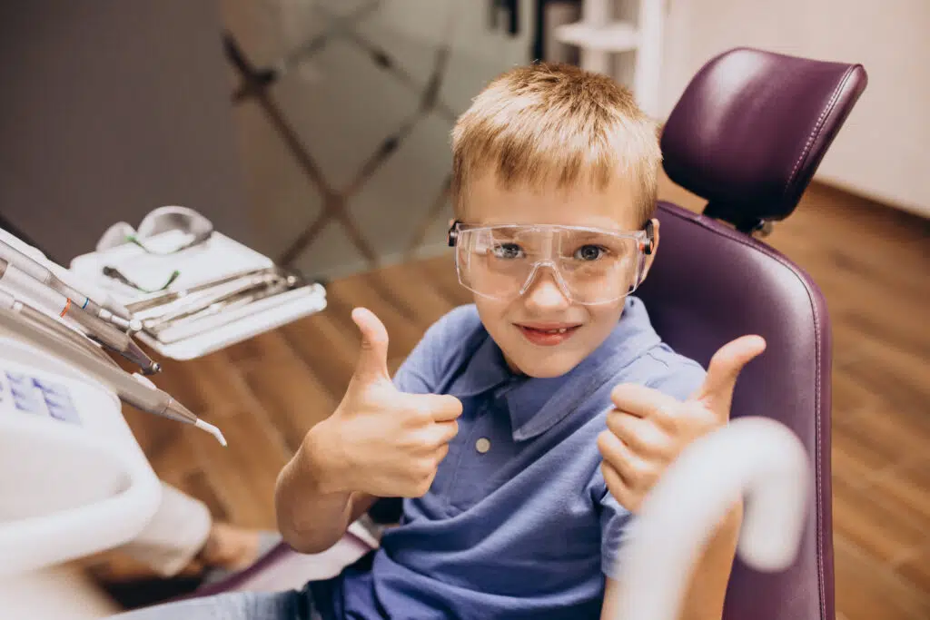 pediatric dental patient hold thumbs up in dental chair